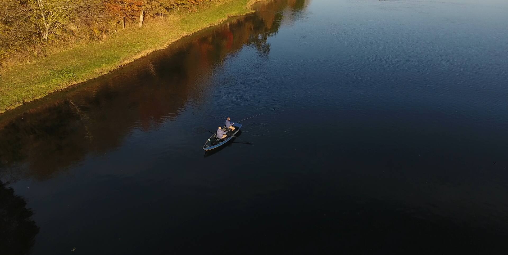 Aerial view of a boat fishing the Tweed below the autumn bank in evening light