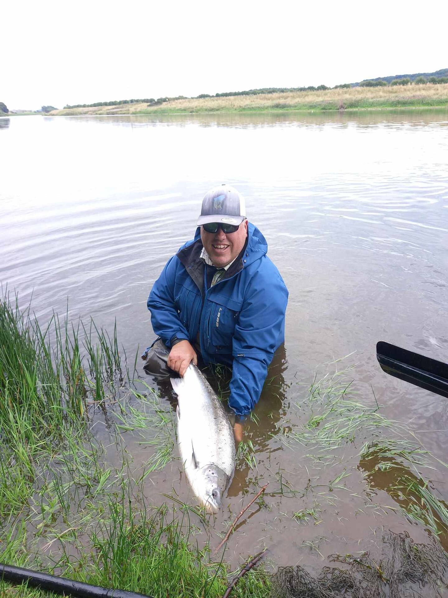 An angler in the river holding a fresh salmon in the water before release