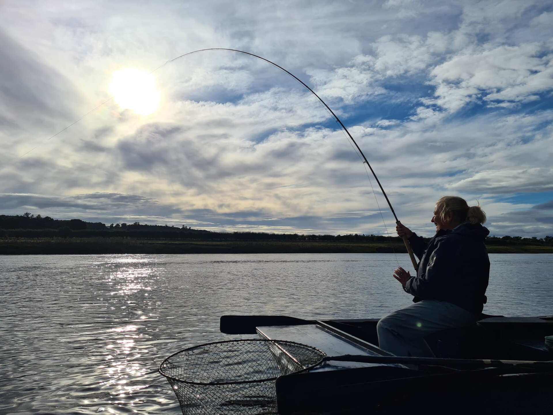 Playing a salmon from the boat on a bright day at Upper North Wark