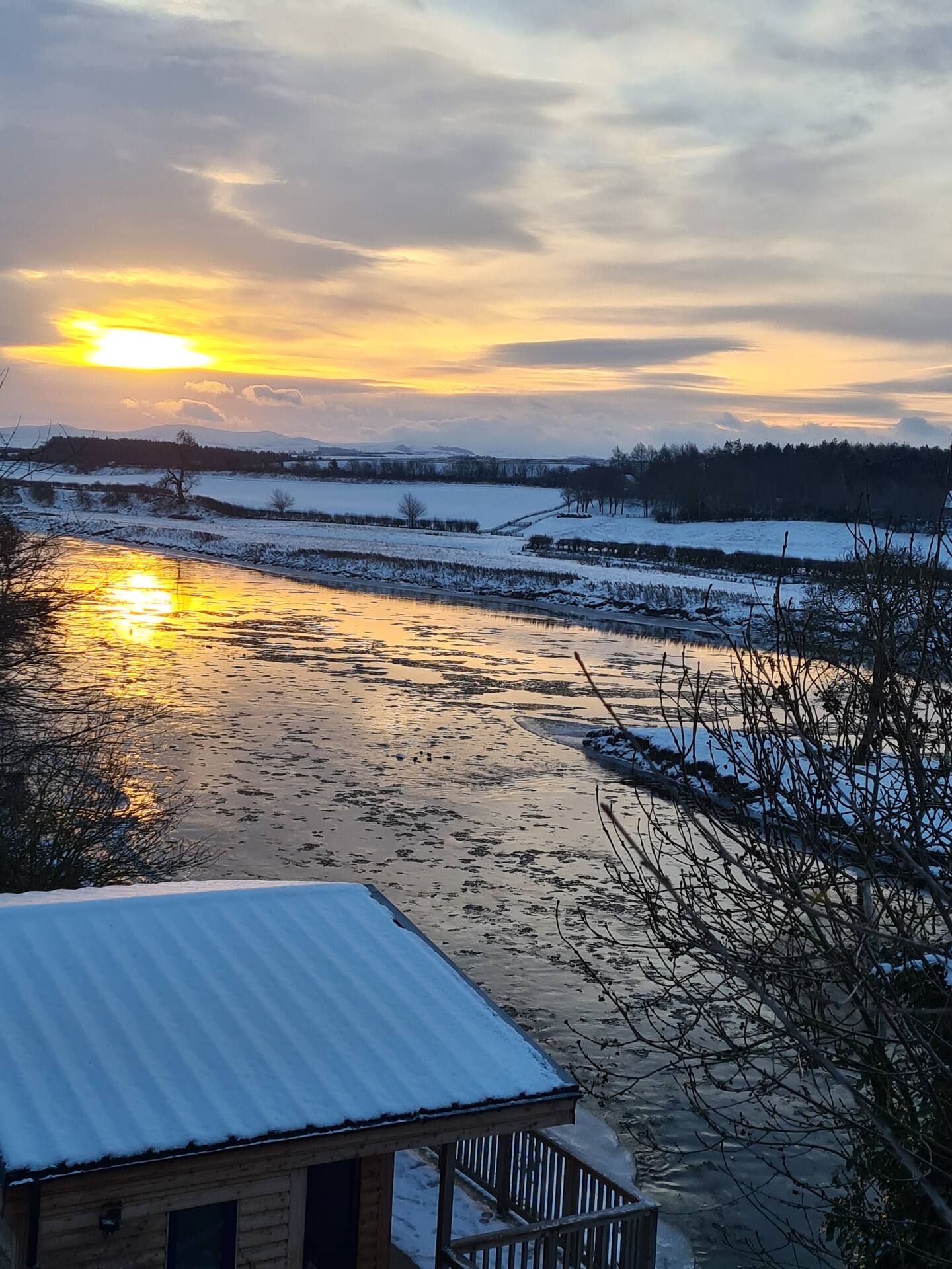 Winter sunset over the icy Tweed seen from above the snow-covered fishing hut